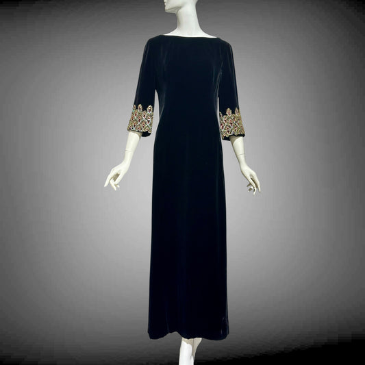 Vintage 1960s Black velvet dress with gold embellishments on sleeves and hem, displayed on a mannequin against a gray background.